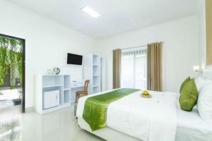 a white bedroom with a bed and a television at Kesari Glory Nusa Penida by Pramana Villas in Nusa Penida