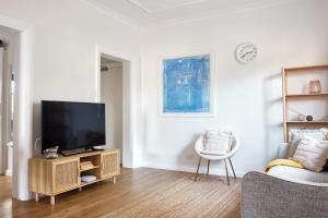 a living room with a flat screen tv and a chair at Manly Cosy Retreat - Short walk to beach in Sydney