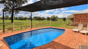 a swimming pool in a yard with a fence at Country Gardens Motor Inn in Cowra