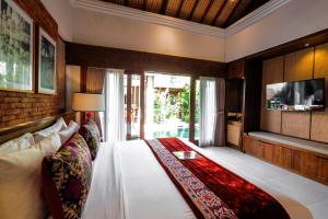 a bedroom with a large bed and a tv at Sampatti Villas in Seminyak
