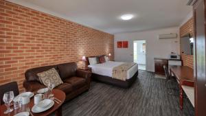 Habitación de hotel con cama y sofá en Country Gardens Motor Inn, en Cowra