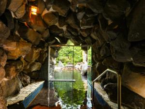 una grotta in pietra con una porta a vetri in una piscina d'acqua di Keiryuso Siorie a Matsumoto