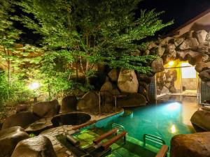 a pool in the middle of a resort with a rock wall at Keiryuso Siorie in Matsumoto