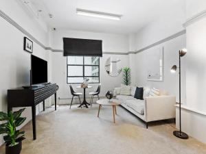 a living room with a white couch and a piano at Lovely 1-Bedroom Unit in Central Auckland in Auckland