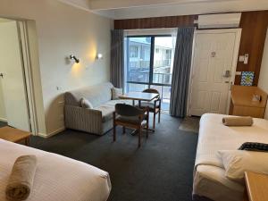 a hotel room with two beds and a table at Banjo Paterson Motor Inn in Lakes Entrance