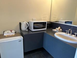 a bathroom with a microwave and a sink at Banjo Paterson Motor Inn in Lakes Entrance