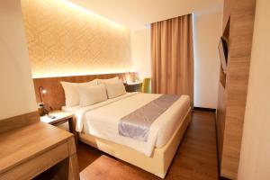 a hotel room with a bed and a television at Odua Weston Jambi in Jambi