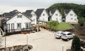 a large house with cars parked in a parking lot at Zain Village in Seogwipo