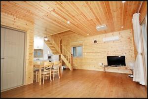 a living room with a wooden ceiling and a television at Zain Village in Seogwipo