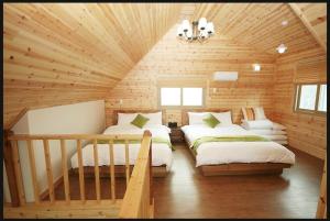 sypialnia z 2 łóżkami w drewnianym domku w obiekcie Zain Village w mieście Seogwipo
