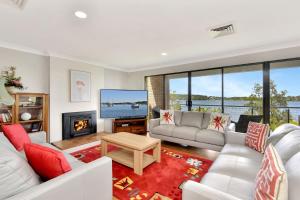 een woonkamer met witte meubels en een open haard bij Lakeview Oasis with Panoramic Waterfront Views at Fishing Point in Fishing Point