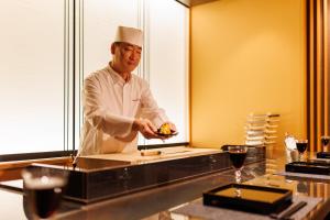 uno chef in piedi in una cucina che prepara il cibo di Yado Shiontei a Yonago