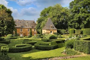 a large garden with hedges and a building at Magnificent Guest House on the bank of the Dordogne river in Siorac-en-Périgord