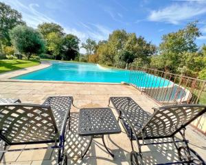 a group of chairs next to a swimming pool at Magnificent Guest House on the bank of the Dordogne river in Siorac-en-Périgord