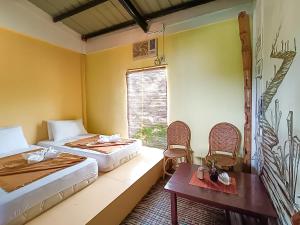 a room with two beds and a table and chairs at Lexias Hostel and Workspace - El Nido in El Nido