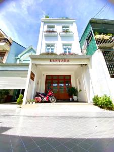 um edifício branco com uma moto estacionada em frente em Lantana Homestay em Da Lat