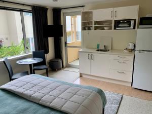 a bedroom with a bed and a kitchen with a table at March Apartments in Dunedin