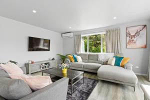 a living room with two couches and a table at Mandeno Magic - Kerikeri Holiday Home in Kerikeri