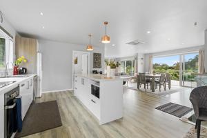 a kitchen with white cabinets and a dining room at Mandeno Magic - Kerikeri Holiday Home in Kerikeri
