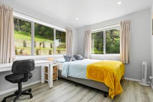 a bedroom with a bed and a desk and windows at Mandeno Magic - Kerikeri Holiday Home in Kerikeri