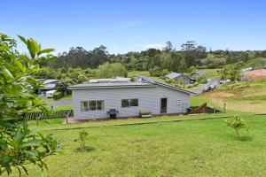 a white house on a hill with a yard at Mandeno Magic - Kerikeri Holiday Home in Kerikeri