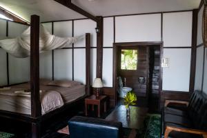 een slaapkamer met een hemelbed en een stoel bij Pomelo Restaurant and Guesthouse's Fishermen Bungalow & A Tammarine Bungalow River Front in Ban Khon