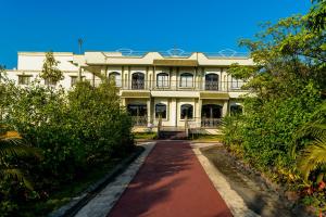 a large white building with a red dirt road at Amidhara Resort in Sasan Gir