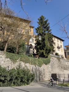 a person riding a bike past a stone wall at Casa Anida in Bergamo