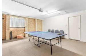 una mesa de ping pong en una habitación con sillas en Hunter Home with POOL / CINEMA ROOM / PING PONG, en Cessnock