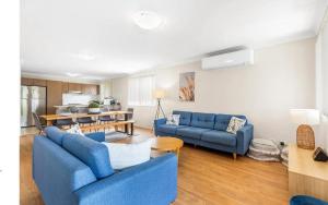 a living room with two blue couches and a kitchen at Hunter Home with POOL / CINEMA ROOM / PING PONG in Cessnock