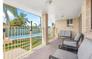 a patio with chairs and a balcony with a pool at Hunter Home with POOL / CINEMA ROOM / PING PONG in Cessnock
