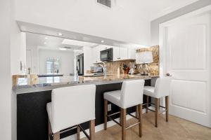 a kitchen with white chairs and a counter top at Villa on Point Brittany 21 in St Petersburg +23 photos