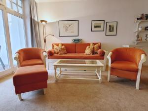 een woonkamer met een oranje bank en 2 stoelen bij Villa Strandidyll in Binz - WG 11 mit Meerblick und zwei Balkonen in Binz