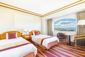 a hotel room with two beds and a window at Hotel Plaza Kobe in Kobe