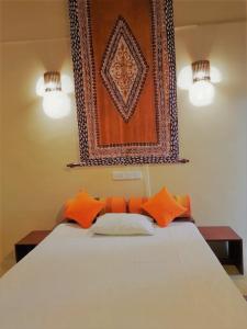 a bed with orange pillows and a picture on the wall at The Tottam Beach Hotel - Trincomalee in Trincomalee