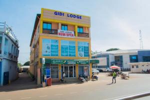 a yellow building on a street with people standing outside at GIDI LODGE in Tamale