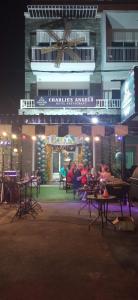 a group of people sitting at tables in front of a building at Charlie's Angels Hotel Restaurant in Rawai Beach