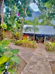 a walkway in front of a building with trees at Phoxay Ngam Resort in Vang Vieng