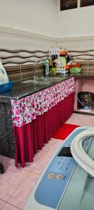 eine Küchentheke mit roten Vorhängen und einer Arbeitsplatte in der Unterkunft Rizki Homestay in Nibung Tebal