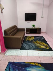 - un salon avec un canapé et une télévision dans l'établissement Rizki Homestay, à Nibung Tebal