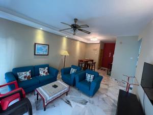 un salon avec des canapés bleus et une table dans l'établissement 2 Bedroom Apartment @ Bay View Port Dickson, à Port Dickson
