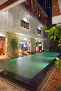 a large swimming pool in a building with a house at Kautaman Hotel in Mataram