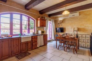 een keuken met houten kasten en een tafel met een aanrecht bij Gozitan Farmhouse with Pool - PP 1 in Il-Wilġa