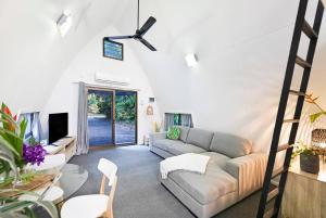 a living room with a couch and a tv at 'Bluey' a Tiny House A-frame Moments to Foreshore in Nightcliff