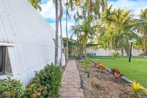 a garden path next to a white building with palm trees at 'Bluey' a Tiny House A-frame Moments to Foreshore in Nightcliff