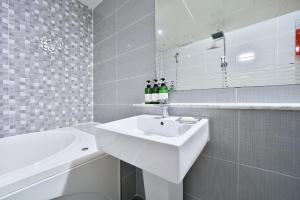 a white bathroom with a sink and a bath tub at B&B Hotel in Busan