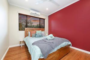 um quarto com uma cama e uma parede vermelha em A Tropical Pool Paradise in Rapid Creek em Nightcliff