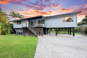 a large house with a staircase and grass at A Tropical Pool Paradise in Rapid Creek in Nightcliff