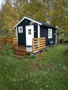 Cette cabine en noir et blanc dispose d'une terrasse en bois. dans l'établissement Countrycabin Bergslagen stuga, à Ramsberg