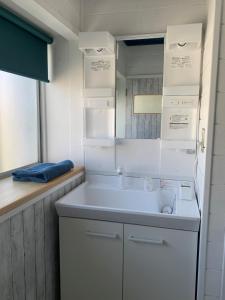- une cuisine blanche avec un évier et un miroir dans l'établissement Ramjet Sotoura Beach House Shimoda, à Shimoda